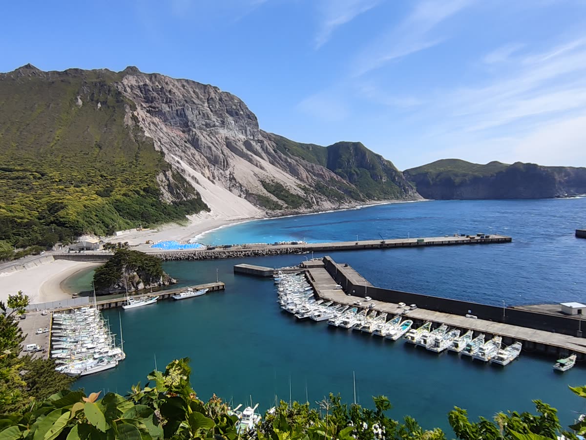 神津島の港と白い砂浜、背後の緑の山