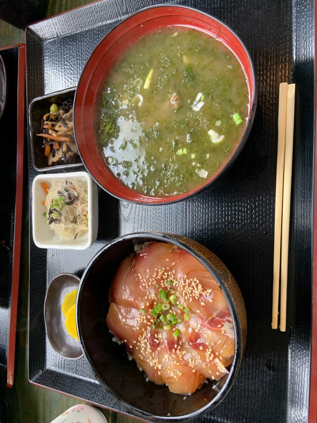 漬けにした白身魚をのせた丼と、青のりの浮いた味噌汁、小鉢の定食